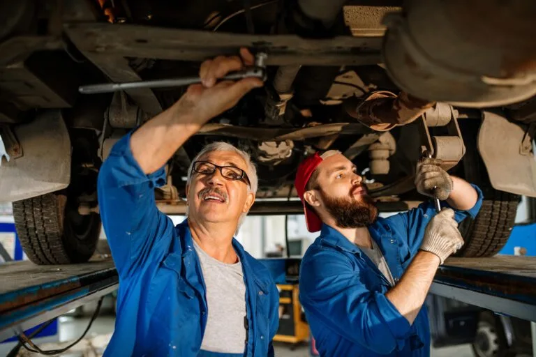 Two technicians repairing a car engine at the garage