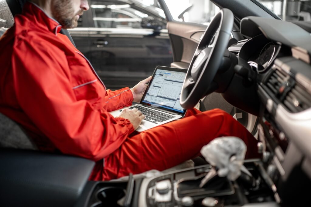 Auto mechanic diagnosing car with computer