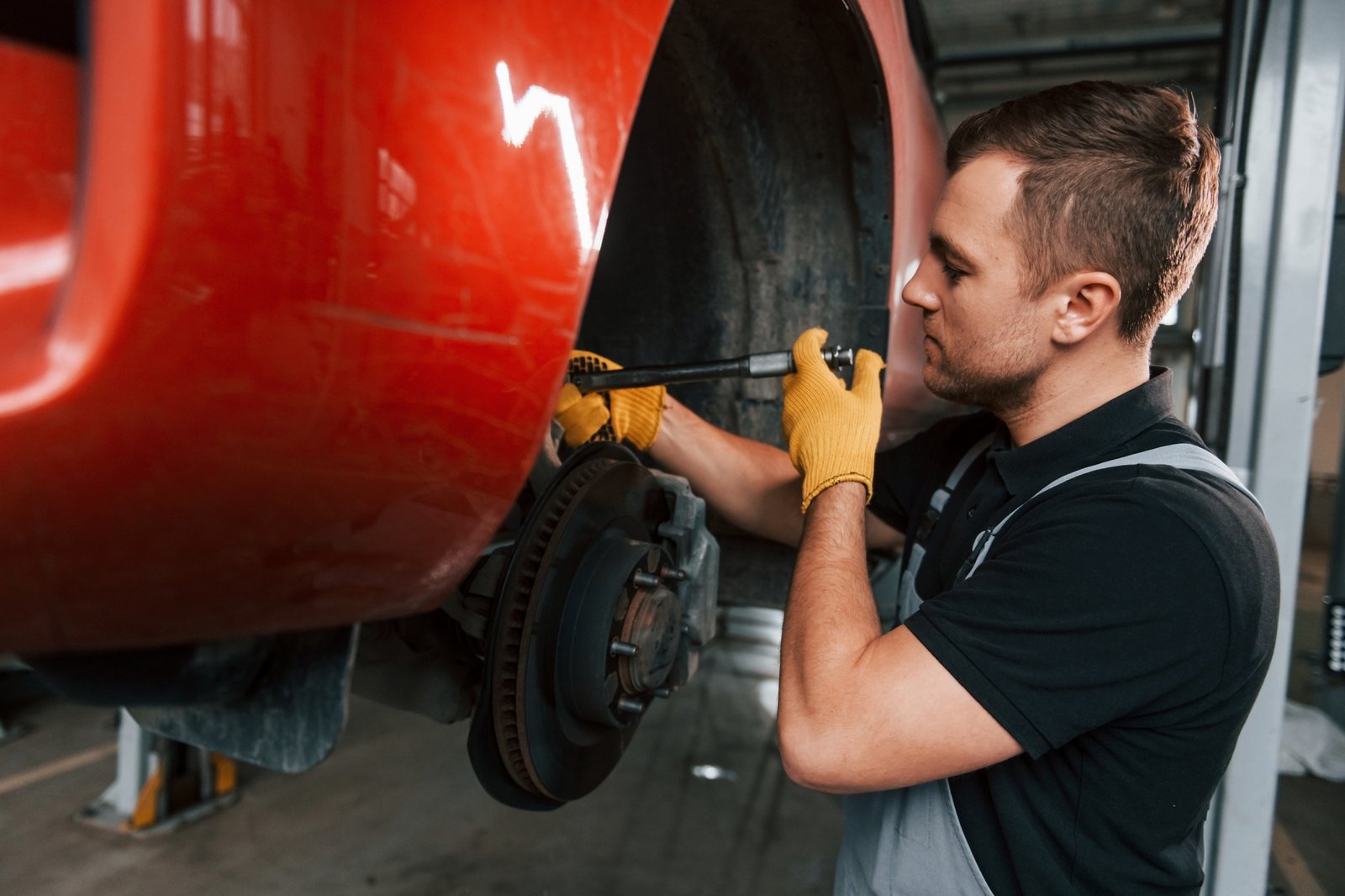 Fixing breaks. Man in uniform is working in the auto service